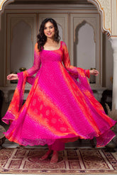 Woman wearing a vibrant pink and orange traditional outfit in an ornate indoor setting.